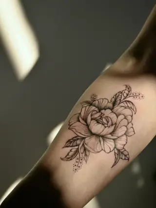Piwonia z liśćmi i drobnymi kropkami po bokach w czarnym cieniowaniu na wewnętrznej stronie ręki – tatuaż Oli, SHADY TATTOO Wieluń