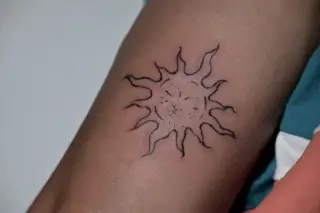 Konturowe słońce z falującymi promieniami i kropkowaną twarzą w środku na ramieniu – tatuaż Oli, SHADY TATTOO Wieluń