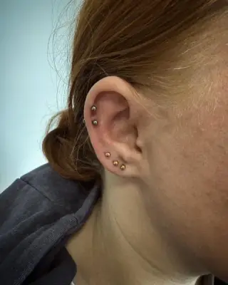 Kompozycja kilku kolczyków w uchu: lobe i helix, ujęcie z boku, piercing w SHADY TATTOO w Wieluniu